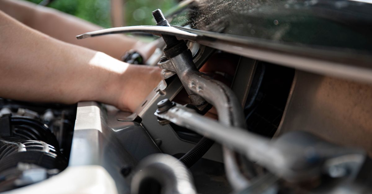 Close-up shot of a mechanic repairing a car engine with focus on tools and hands.